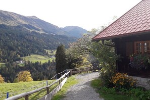Ein Berggemäuer mit einem Kiesweg, der zu einem Holzzaun mit Blick auf ein Tal führte.