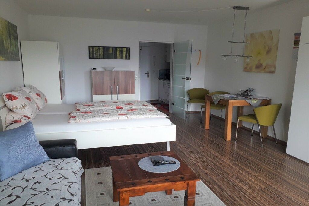 Ein modernes Schlafzimmer mit einem Bett, einem Nachttisch, einem Schreibtisch mit Stühlen und einem Kleiderschrank.