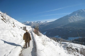 A person walking on a snow-covered path with a mountain in the background. - House Bergblick Apartment 1 "Zinken" (Berchtesgaden)