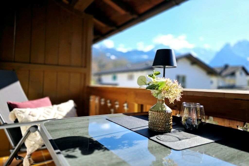 A table with a vase of flowers and a lamp, overlooking a mountain view.