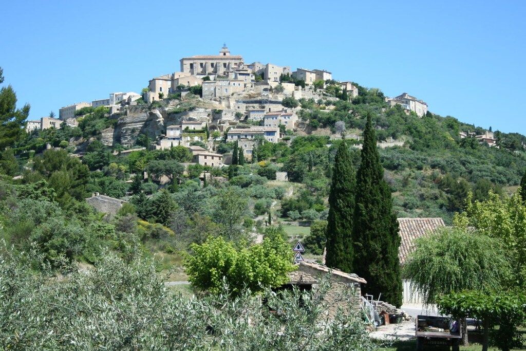Un village perché sur une colline, avec ses bâtiments traditionnels en pierre, une église imposante et une végétation luxuriante.