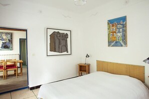 Ein Hotelzimmer mit Bett, Nachttisch, Sessel und einem Bild an der Wand.