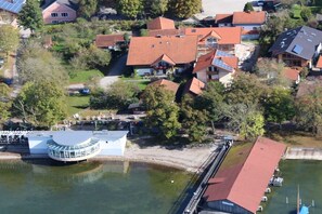 An aerial view of a residential area with houses, a dock, and a circular building near a body of water. - 3 on the shore of Lake Chiemsee at Paulfischer (Chieming)