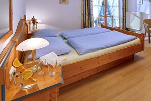 A wooden bed with a wooden headboard, a bedside table with a lamp, and a window with curtains. - 3 on the shore of Lake Chiemsee at Paulfischer (Chieming)