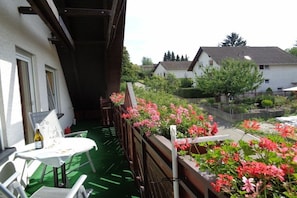 A balcony with a view of a residential area, a table with chairs, and a bottle. - Holiday apartment with 1 bedroom (Oberotterbach)