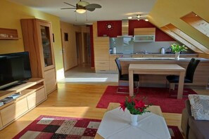 Ein modernes Apartment mit Wohnzimmer, Essbereich, Küchenzeile und einer Treppe zu einer oberen Ebene.