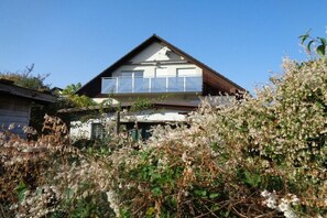 A two-story house with a balcony, surrounded by overgrown vegetation. - Holiday apartment with 1 bedroom (Oberotterbach)