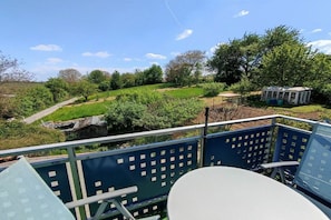 A balcony with a view of a garden and a small pavilion. - Holiday apartment with 1 bedroom (Oberotterbach)
