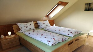 Un letto singolo con lenzuola a motivi floreali, un comodino con una lampada e una testata in legno.