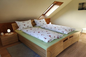 A single bed with floral bedding, a nightstand with a lamp, and a wooden headboard. - Holiday apartment with 1 bedroom (Oberotterbach)