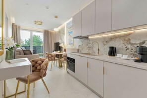 Une cuisine moderne avec un revêtement mural en marbre, une machine à café et un coin repas comprenant une table ronde et des chaises.