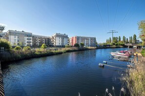 A river with a dock and boats, surrounded by modern buildings and greenery. - Air-conditioned Apartment with a View of the Water | Close to the City Centre (Gdańsk)