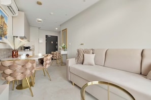 Uma sala de estar moderna com um sofá, área de jantar com cadeiras e cozinha com máquina de café.