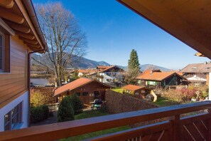 Ein Holzhaus mit Balkon, das auf ein Dorf und Berge blickt.