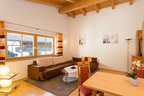 Una sala acogedora con un sofá marrón, una mesa de comedor y un ventanal con cortinas.