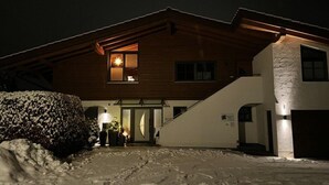 A two-story building with a wooden facade and a stone wall section. - Holiday apartment with 1 bedroom (Oberammergau)