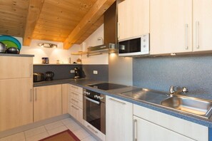 Una cocina moderna con armarios de madera, un lavamanos de acero inoxidable y un microondas.
