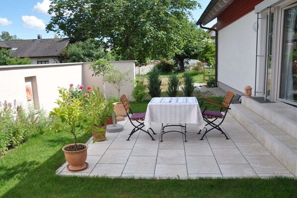 A patio with a table and chairs, surrounded by potted plants and a lawn. - Holiday apartment in Salem with swimming pool (Salem)