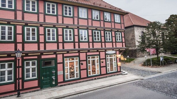 Un edificio tradicional con entramado de madera, múltiples ventanas y una puerta verde.