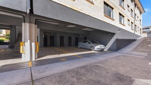 A parking garage with a car parked in one of the bays. - Pacific Court 10 by HolidayCo. (THE ENTRANCE)