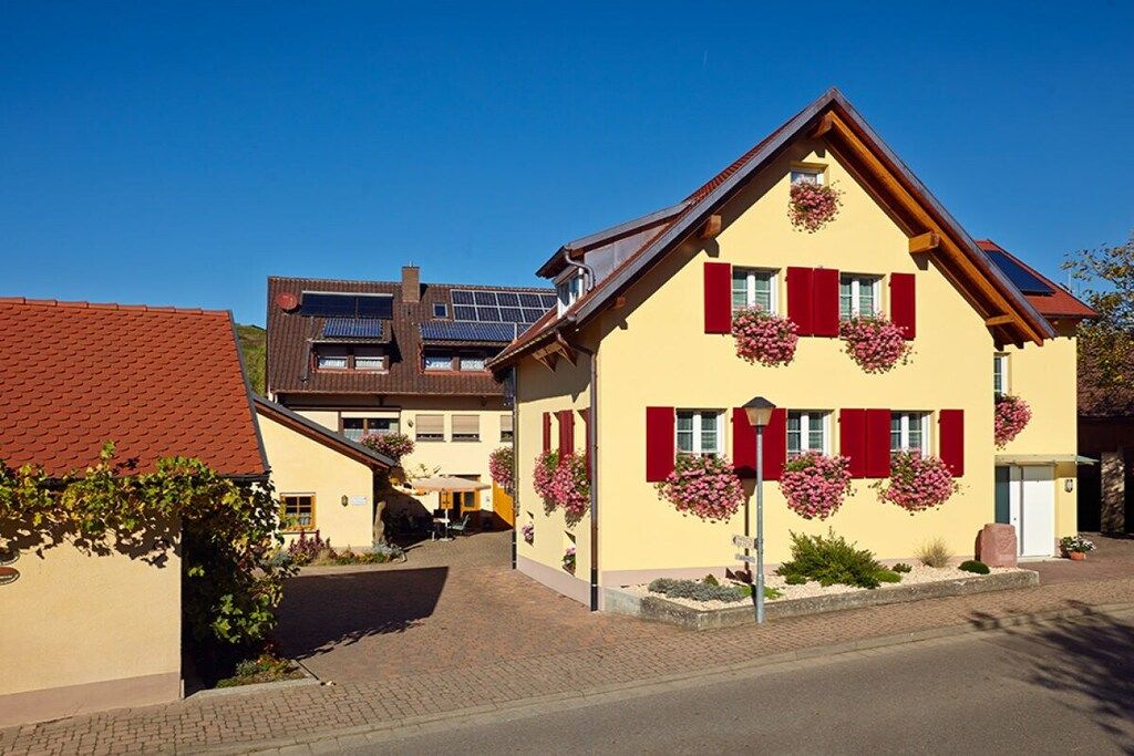A traditional building with a sloped roof, red shutters, and flower boxes on the windows.