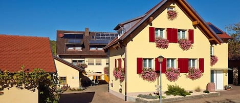 A traditional building with a sloped roof, red shutters, and flower boxes on the windows.