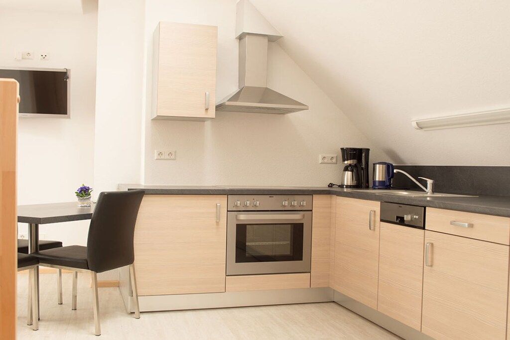 A compact kitchen with a built-in oven, a coffee maker, and a sink.