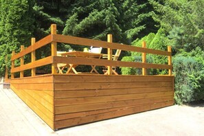 A wooden deck with a railing, surrounded by dense green foliage. - Holiday apartment in Burrweiler with Wi-Fi (Burrweiler)