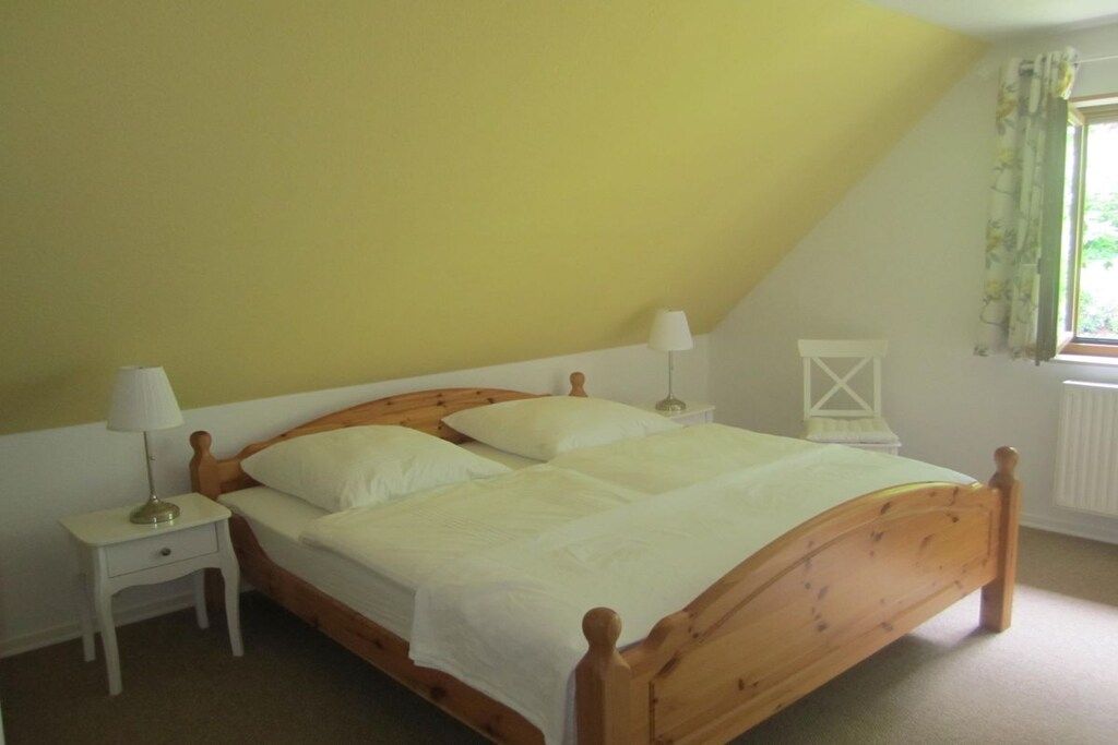 Ein Einzelbett mit Holzbettgestell und weißer Bettwäsche in einem Zimmer mit gelben Wänden.