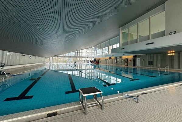 An indoor swimming pool with clear lanes, a starting block, and a tiled floor. - Holiday apartment with 1 bedroom (Sierksdorf)