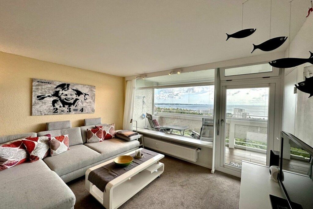 A modern living room with a sofa, coffee table, and artwork on the wall.