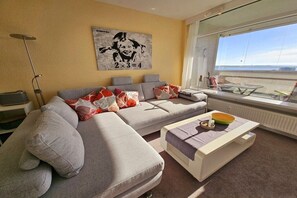 Ein modernes Wohnzimmer mit einer Couch, einem Couchtisch und einem großen Fenster mit Blick.