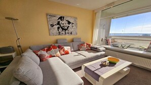 Una sala de estar moderna con un sofá, una mesa de centro y un amplio ventanal con vistas.