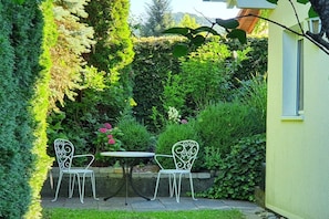 A patio with two chairs and a table, surrounded by lush greenery and a hedge. - Villa Maja Lake Constance (Markdorf)