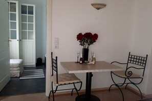 A dining area with a table, chairs, a vase with red flowers, wine glasses, and a bottle. - Villa Maja Lake Constance (Markdorf)