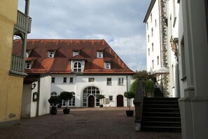 A courtyard with a building featuring a red-tiled roof, arched doorways, and potted plants. - Villa Maja Lake Constance (Markdorf)