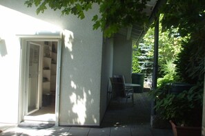 A covered outdoor area with a patio table and chairs, a door leading to a room, and potted plants. - Villa Maja Lake Constance (Markdorf)
