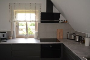 A modern kitchen with a built-in stove, a toaster, and a coffee maker on the countertop. - Holiday apartment with 1 bedroom (Ellingen)