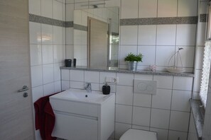 Een badkamer met een witte wastafel, spiegel en een handdoekhouder.
