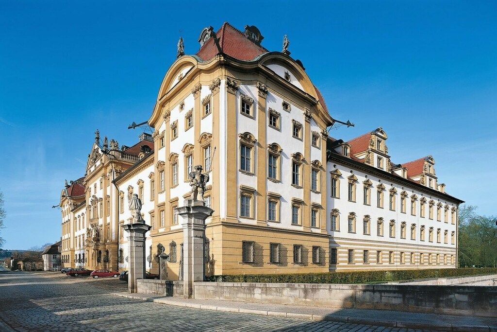 A historic building with classical architecture, featuring a symmetrical facade, multiple windows, and statues.
