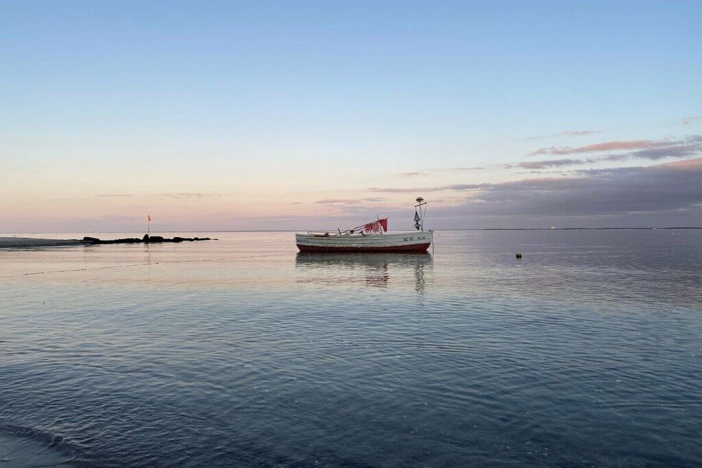 A calm body of water with a single boat anchored in the center.