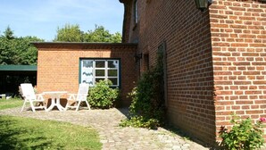Edificio de ladrillo con un pequeño patio que tiene una mesa y sillas.