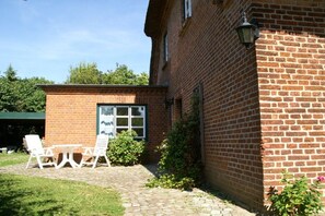 A brick building with a small patio area featuring a table and chairs. - Holiday apartment with 1 bedroom (Sierksdorf)