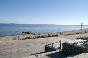A wooden boardwalk leading to a beach with a clear view of the water and distant land. - Holiday apartment with 1 bedroom (Sierksdorf)