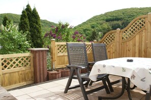 An outdoor patio with two chairs and a table, surrounded by a wooden fence and a view of a green hillside. - Holiday apartment with 1 bedroom (Treis-Karden)