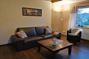 Una sala de estar con un sofá, una mesa de centro con un florero, una lámpara de pie y una silla.