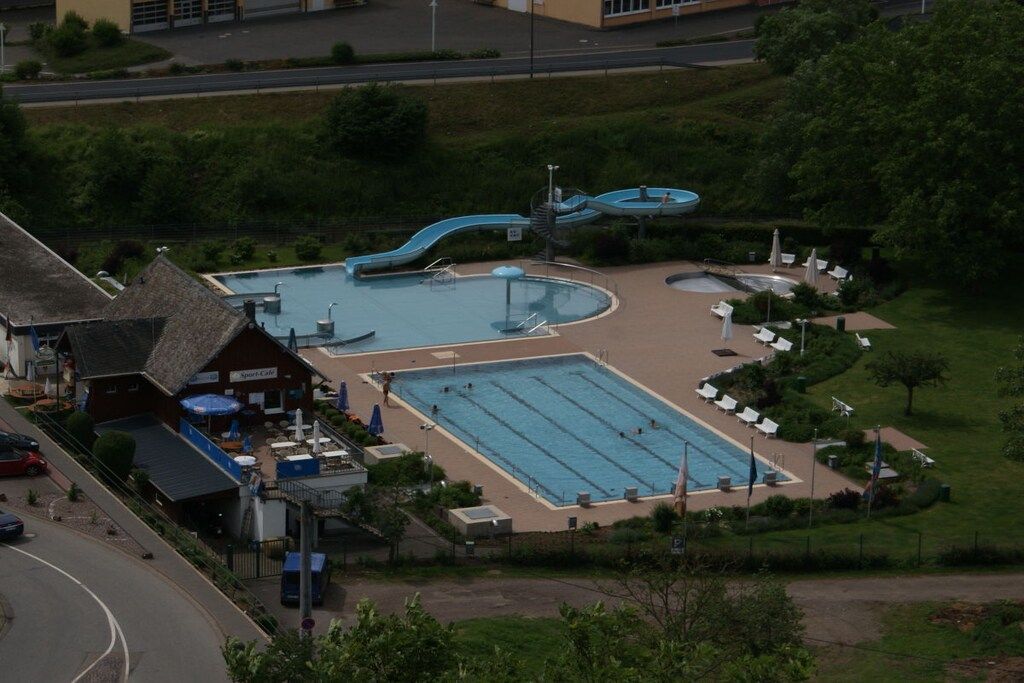 A swimming pool complex with a water slide, multiple lanes, and lounge areas.