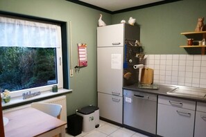A kitchen with a window, a white refrigerator, a sink, and a trash bin. - Holiday apartment with 1 bedroom (Treis-Karden)