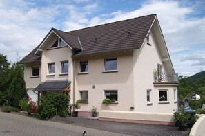 A two-story residential building with a sloped roof, multiple windows, and a balcony. - Holiday apartment with 1 bedroom (Treis-Karden)