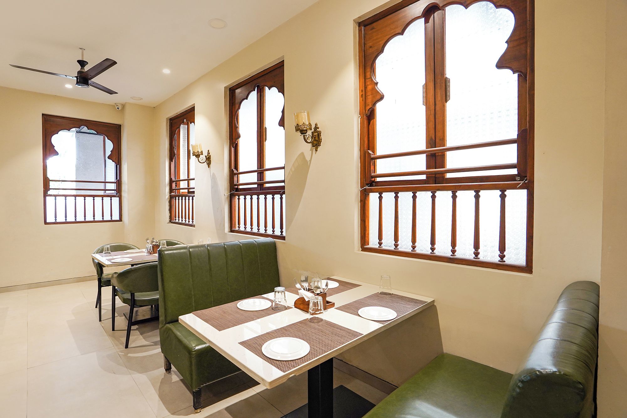 A dining area with a table set for four, a green booth, and a ceiling fan.